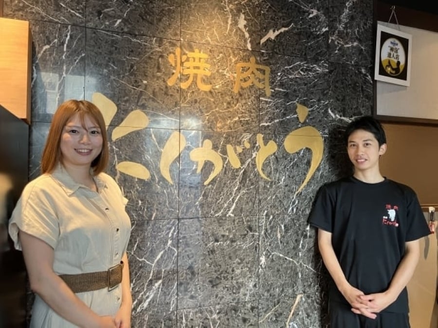 エントランスで写真を撮る伊藤歩社長と伊藤店長補佐